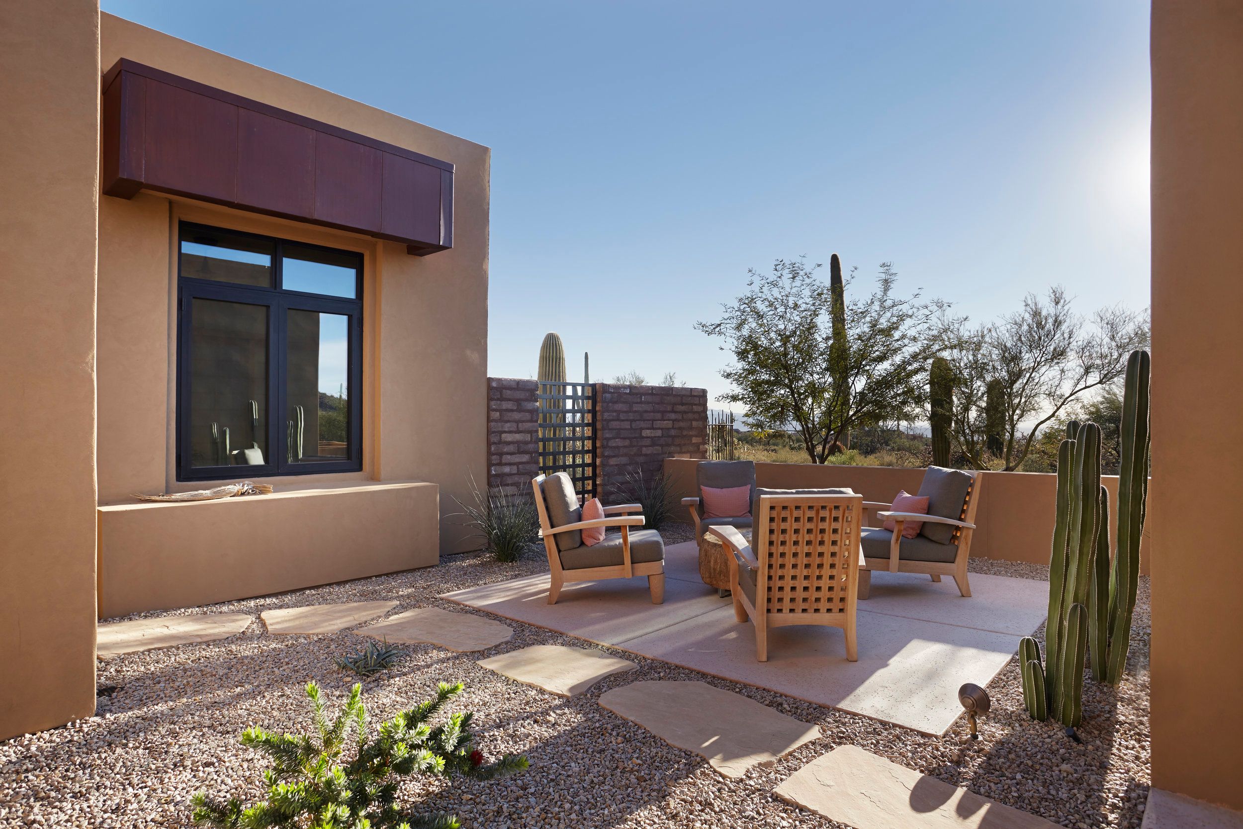 Side courtyard with teak seating, a brick screen wall and desert plantings
