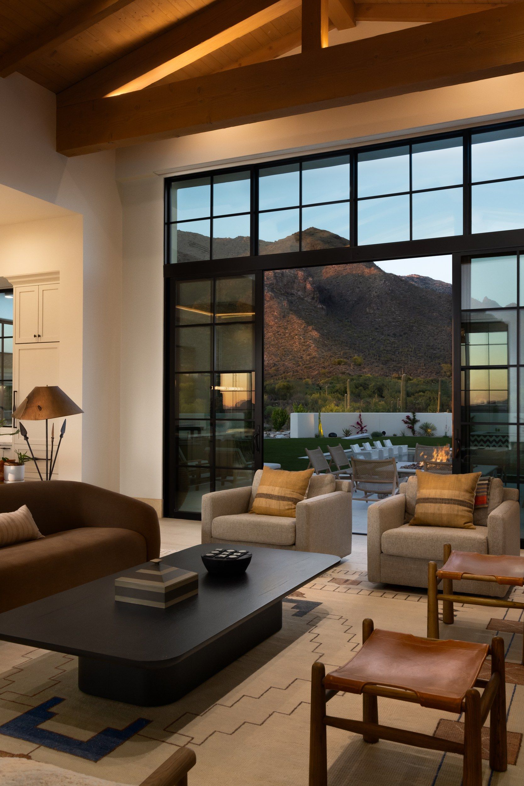 Living room with a wall of black steel windows opening to the terrace and mountains