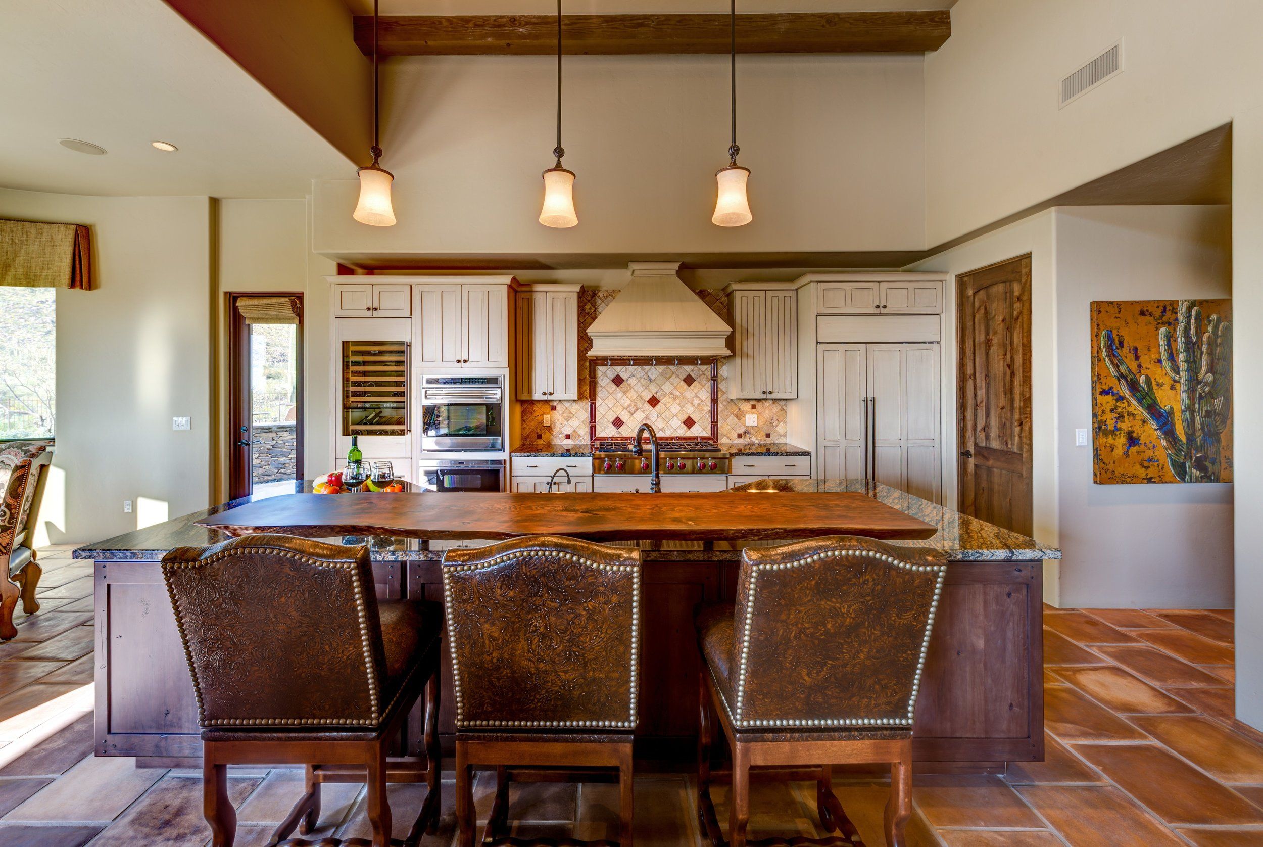 Kitchen with a copper-topped island, leather bar stools and saltillo tile floor