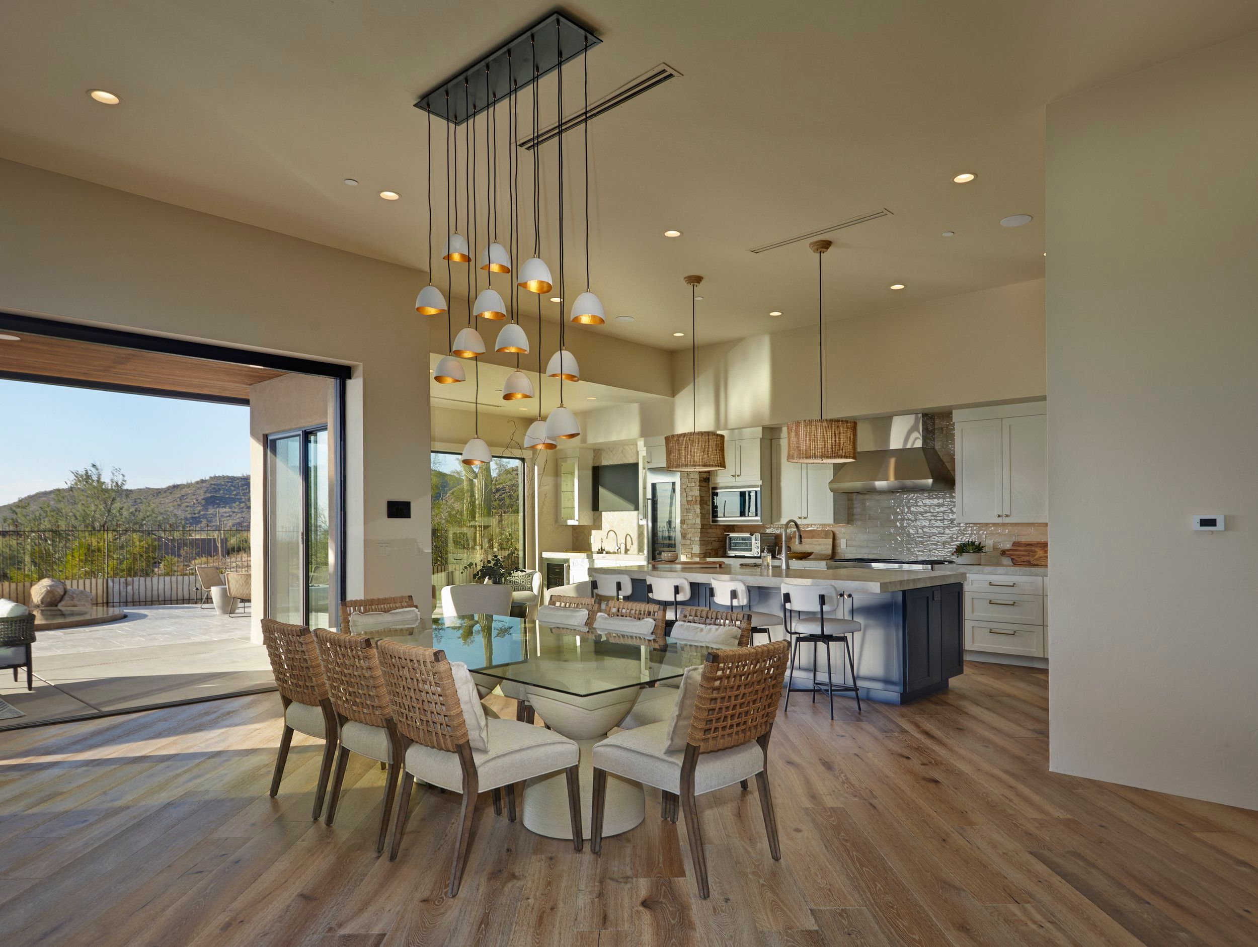 Open dining and kitchen space with woven chairs and a glass-topped table