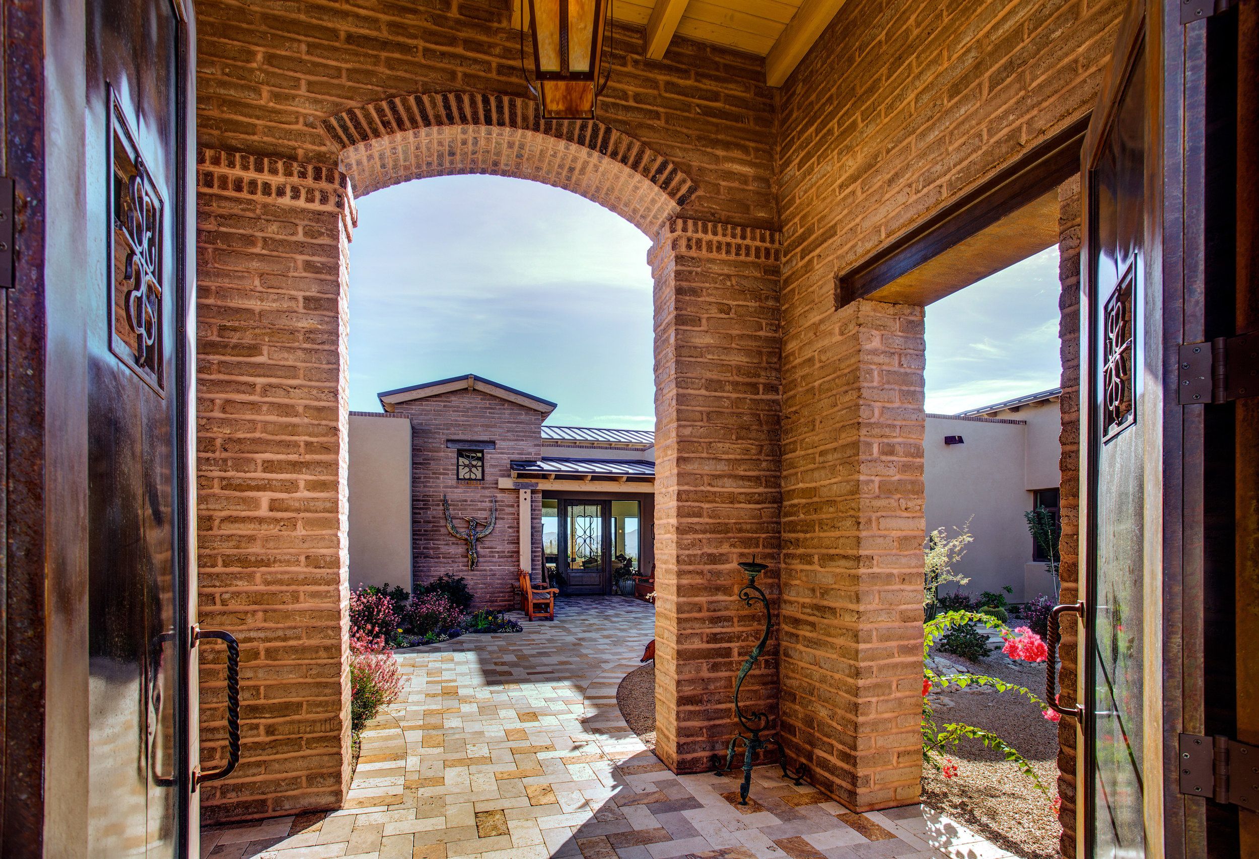 Brick archway entry looking through to a paver courtyard and the front door beyond