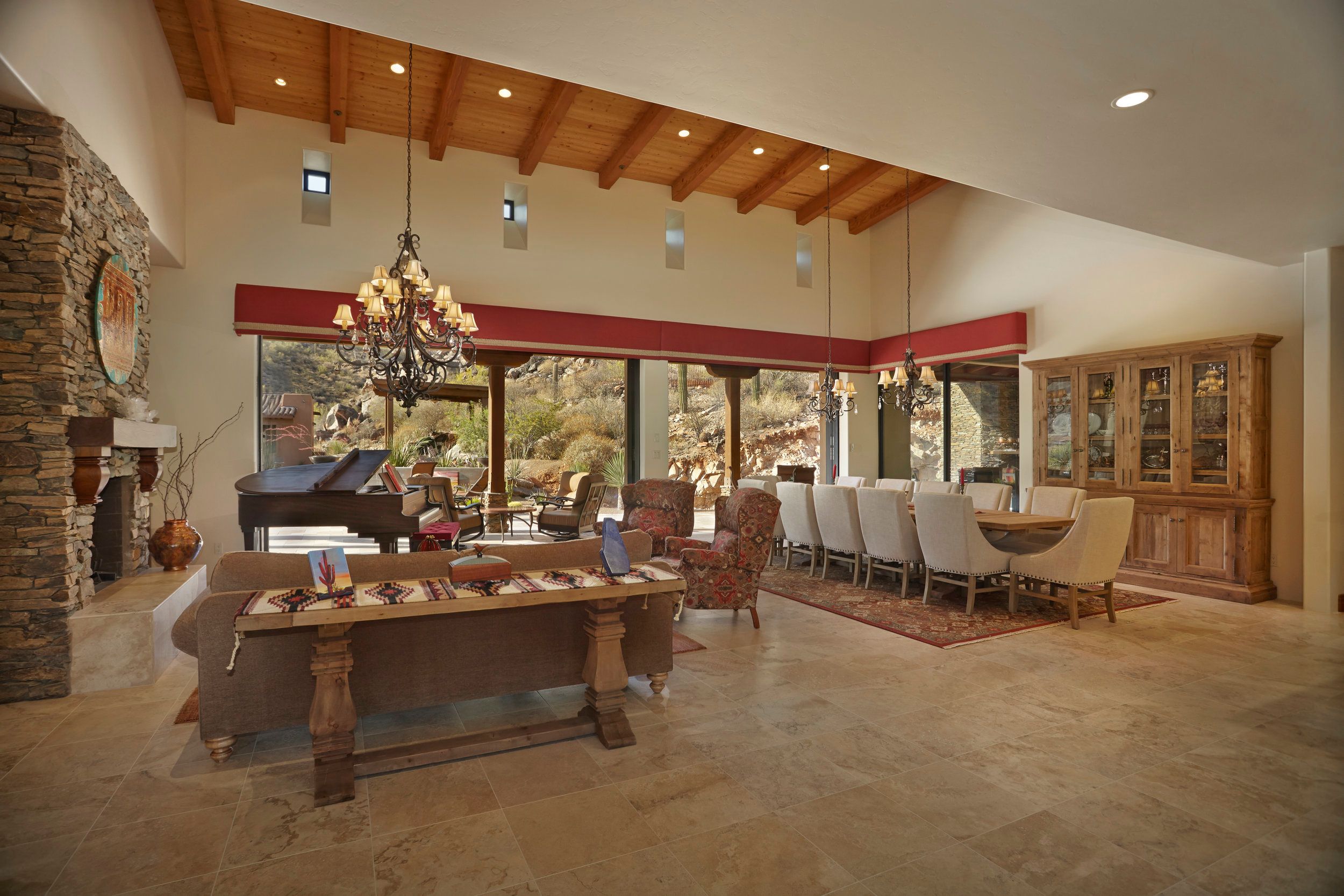 Great room with a vaulted beamed ceiling, iron chandeliers and stone fireplace