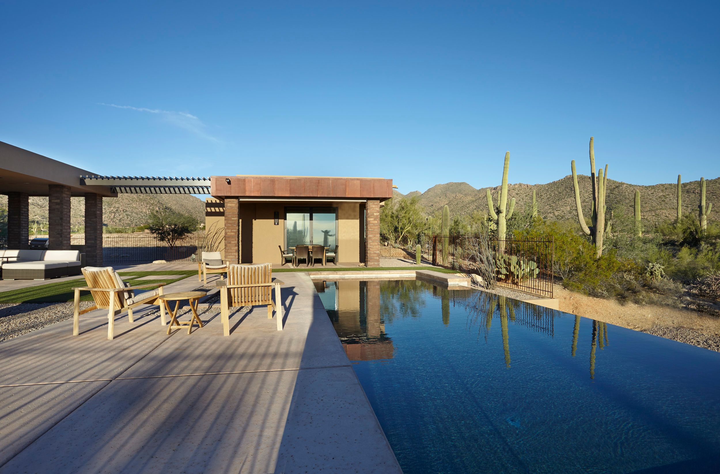 Long negative-edge pool reflecting the covered patio and saguaros