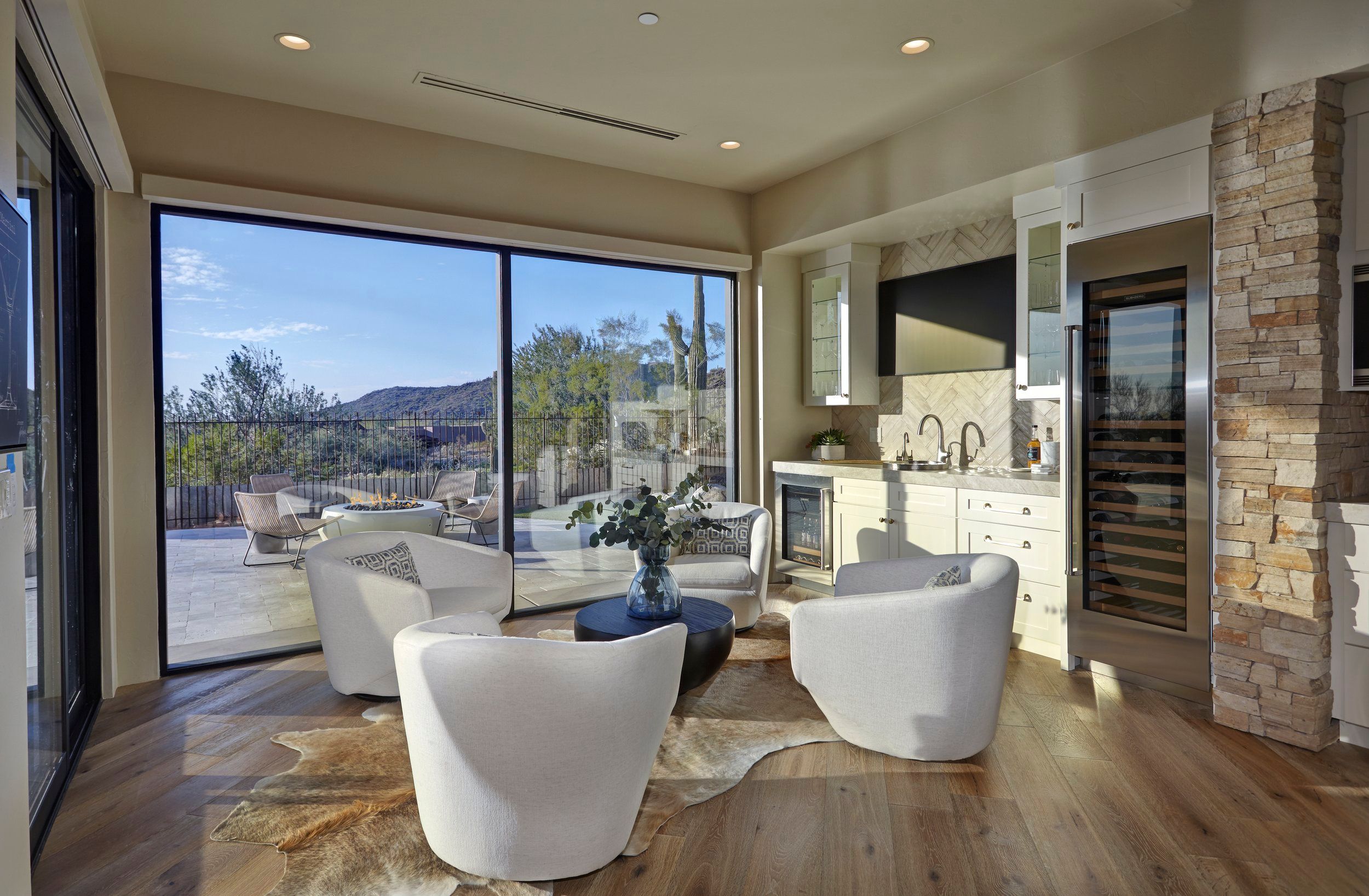Sitting room with swivel chairs, a cowhide rug and full-height glass onto the desert