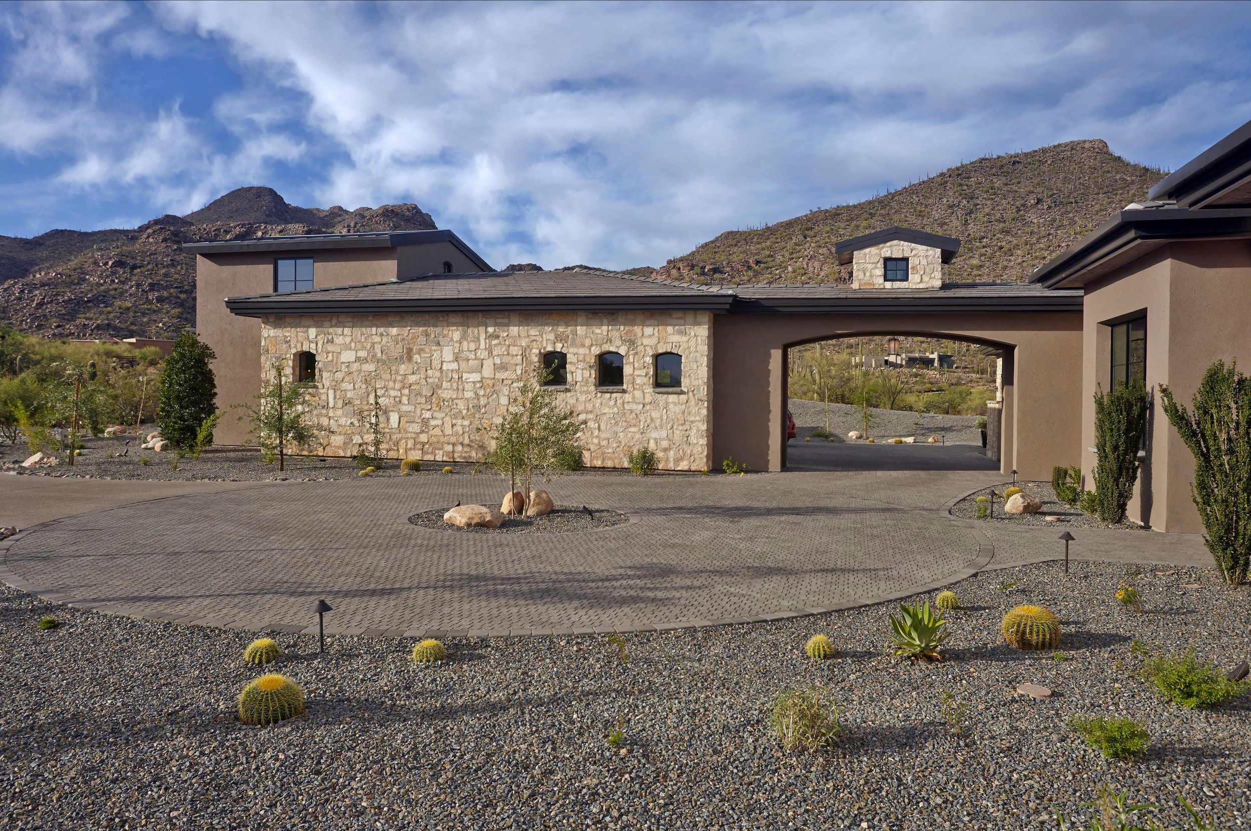 Stone-clad front elevation and motor court with desert gravel landscaping