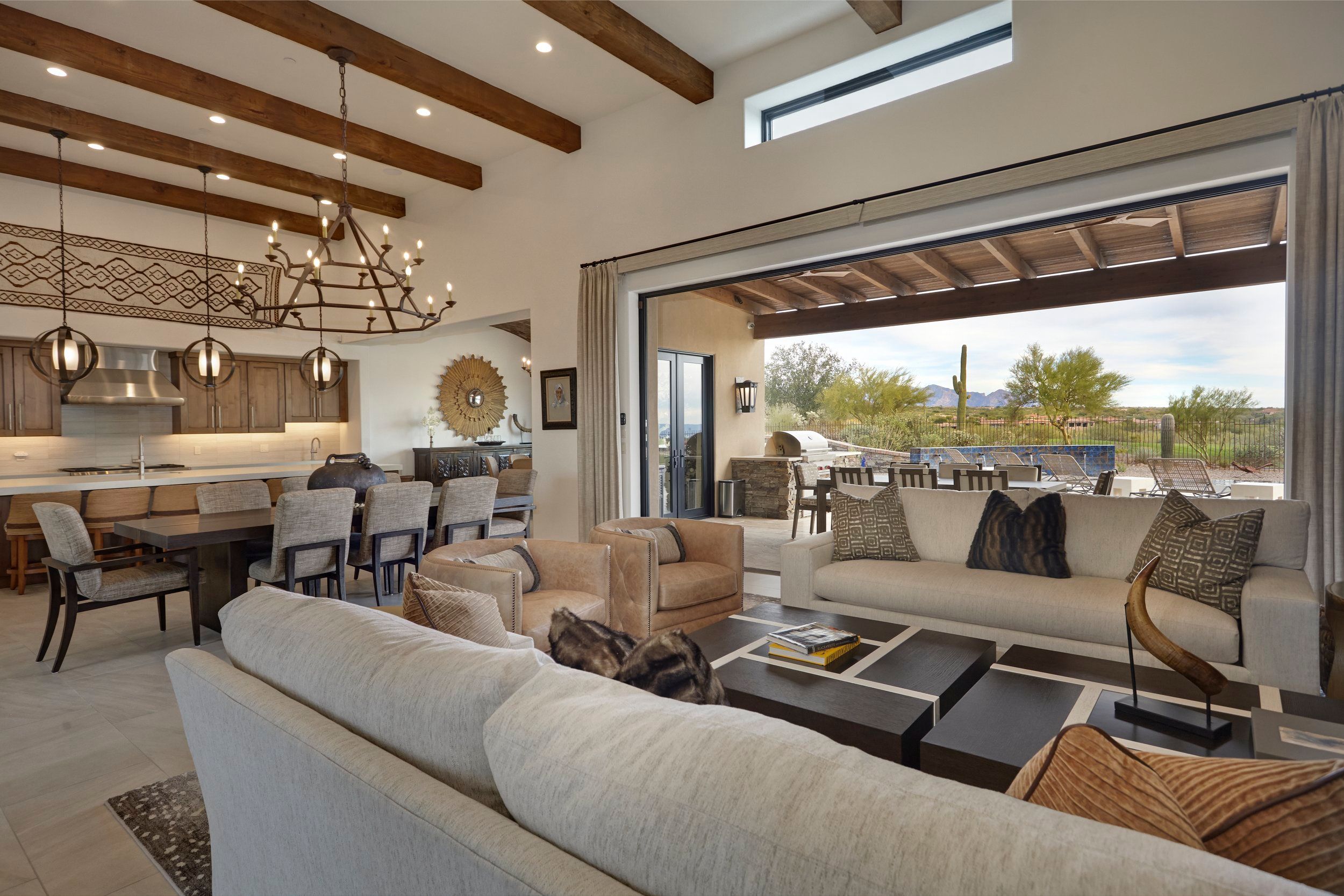 Great room and kitchen under a beamed ceiling, opening onto the covered patio