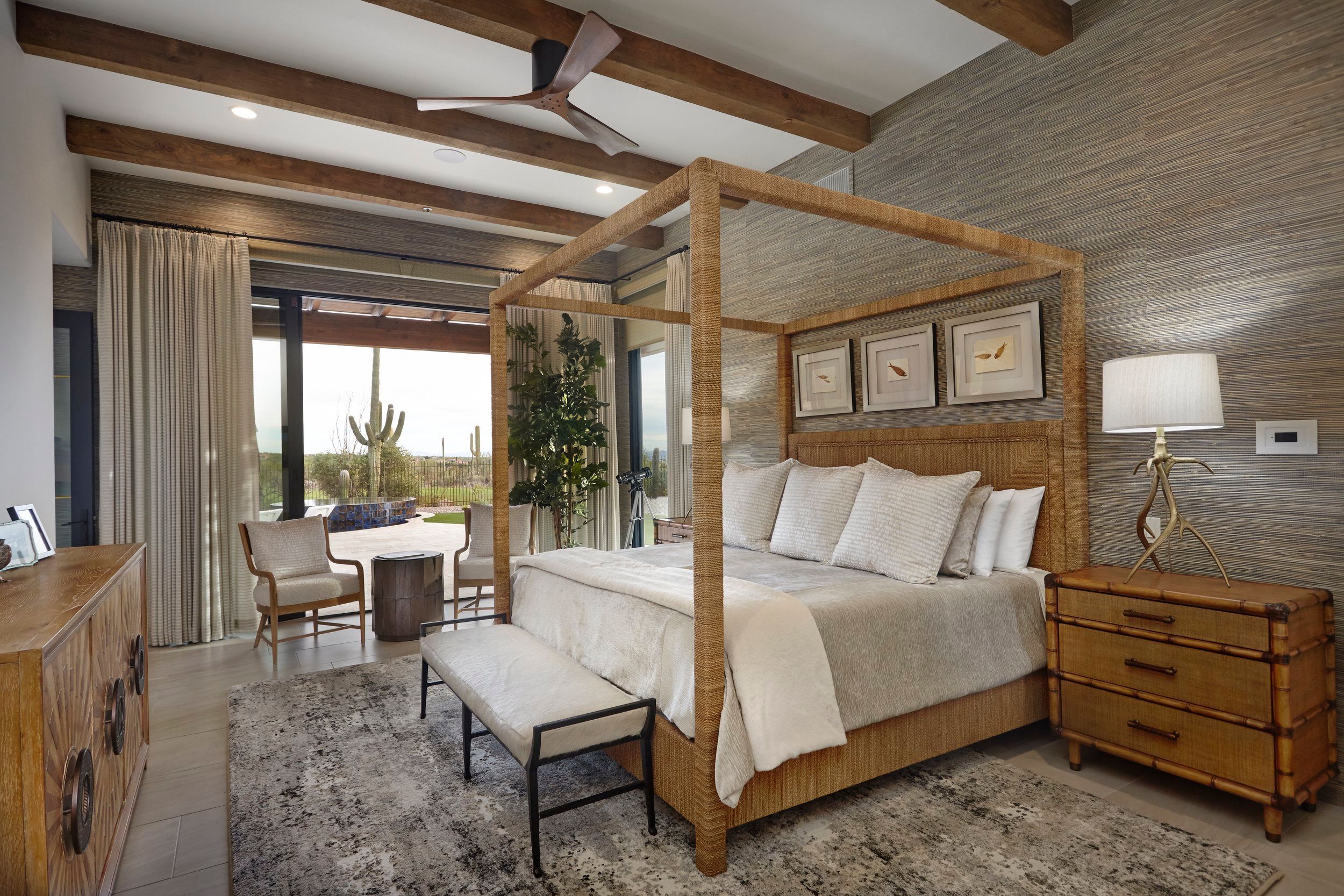 Primary bedroom with a woven four-poster bed, grasscloth wall and patio access