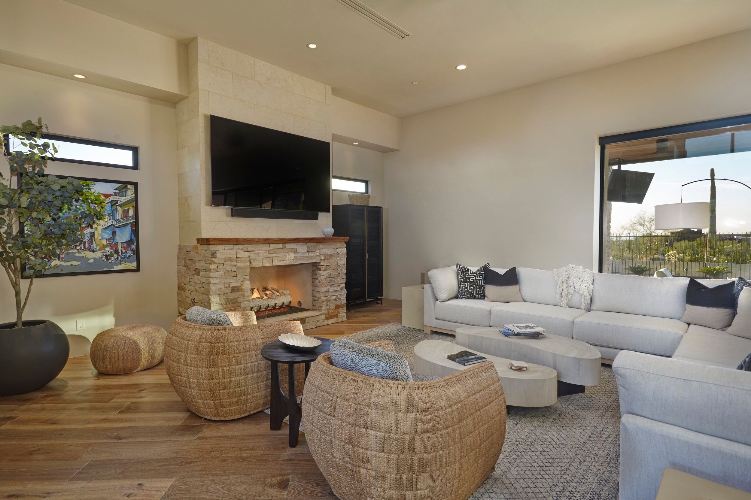 Living room with a stone fireplace, sectional sofa and woven ottomans