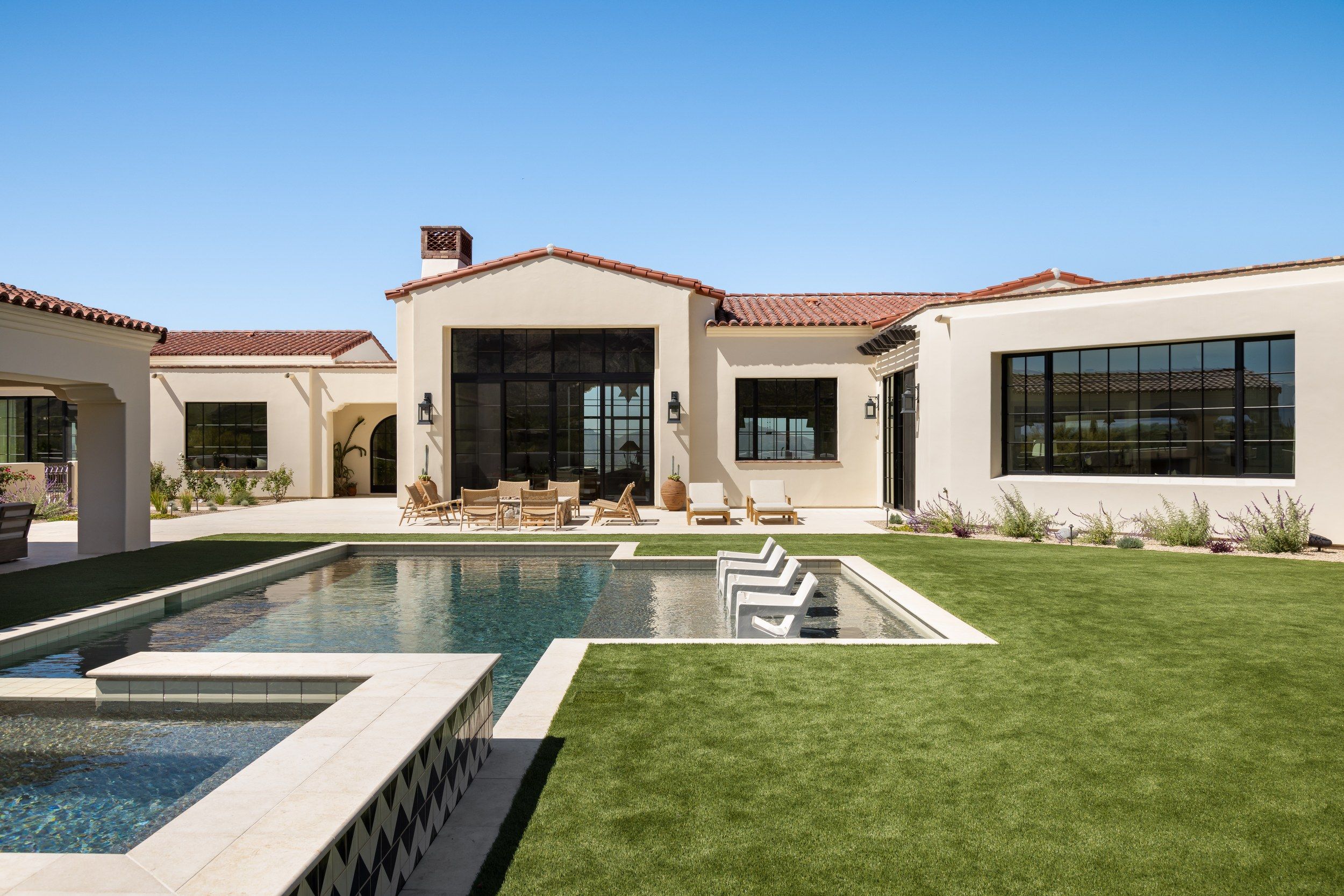 Rear elevation with the lap pool, lawn and covered ramada