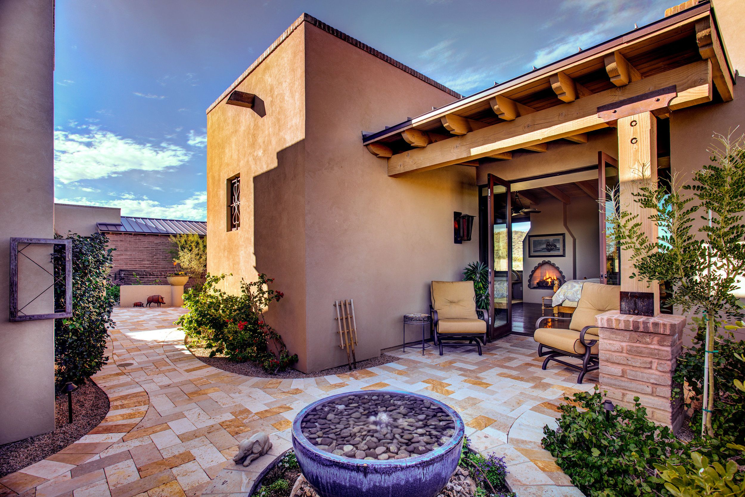 Courtyard with a stone water bowl fountain, patio seating and an outdoor fireplace