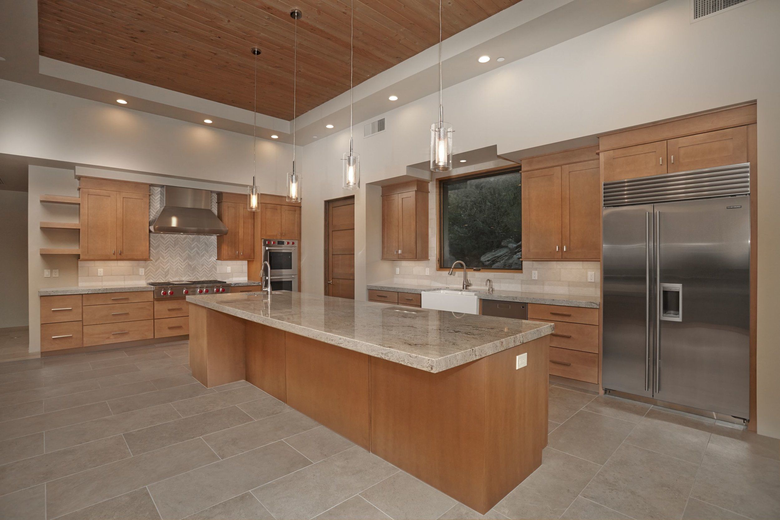 Kitchen with a large island, farmhouse sink and stainless refrigerator