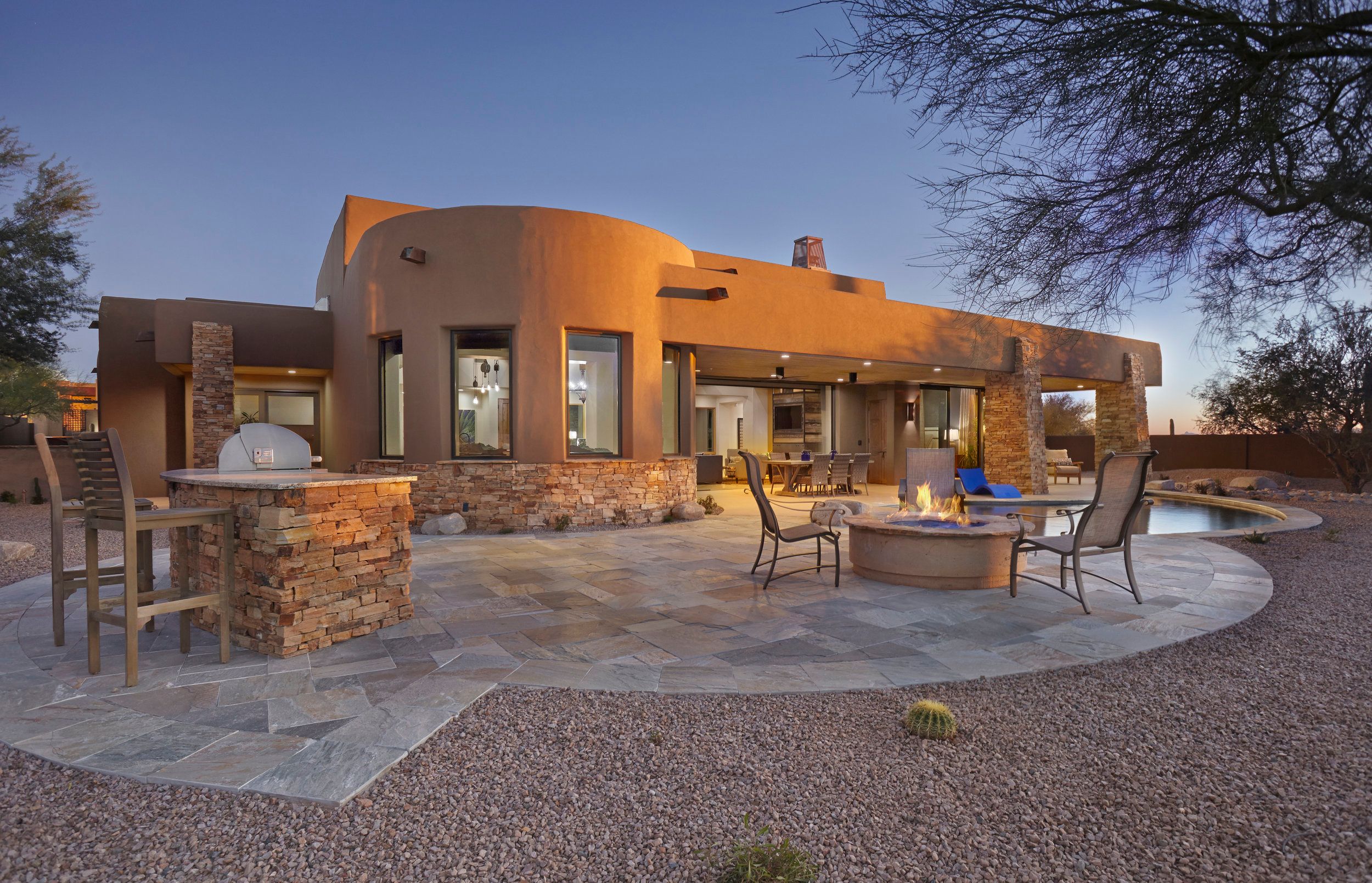Rear elevation at dusk with an outdoor kitchen, fire pit and spa