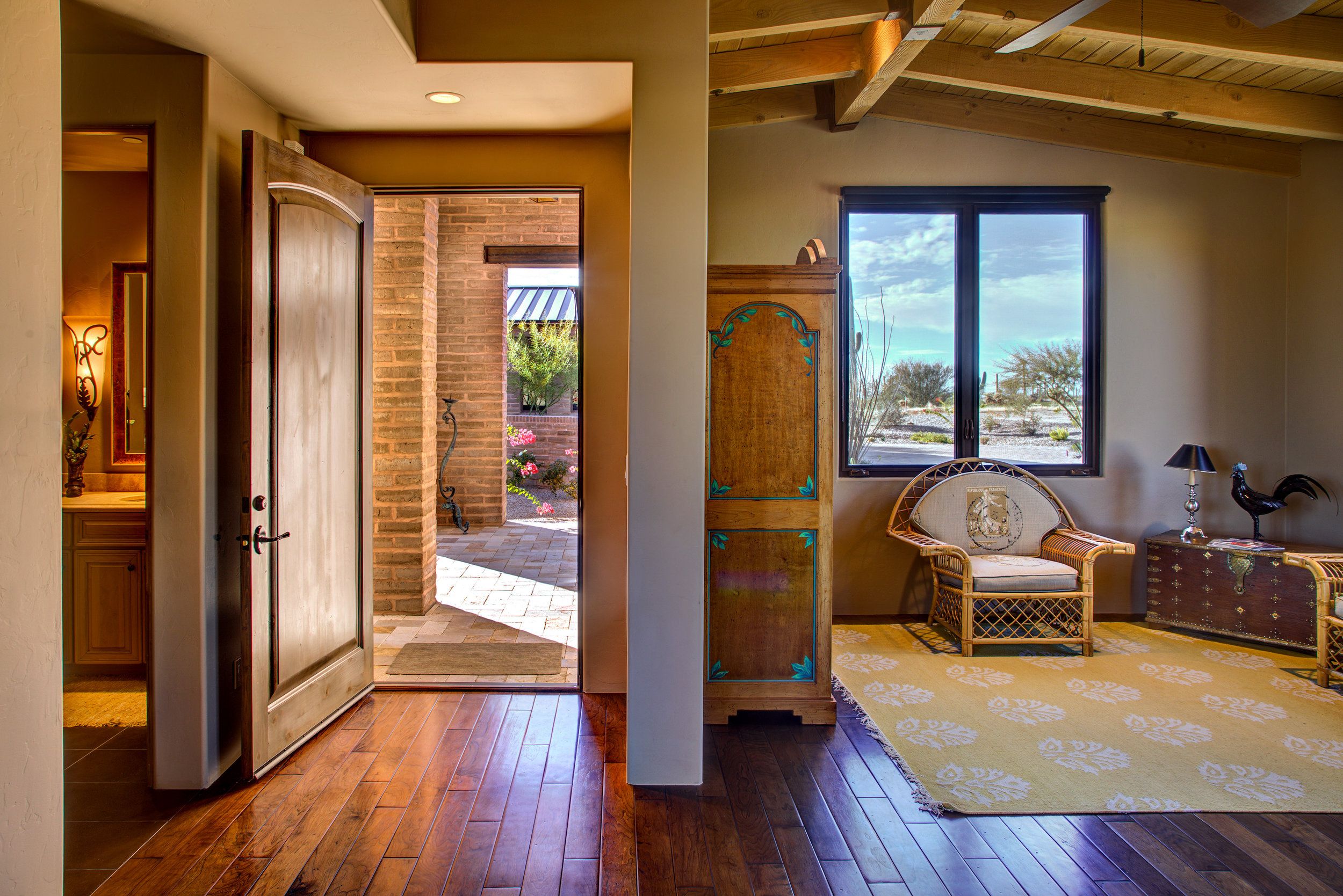 Hallway looking through to a sitting room with a carved wood armoire and desert view