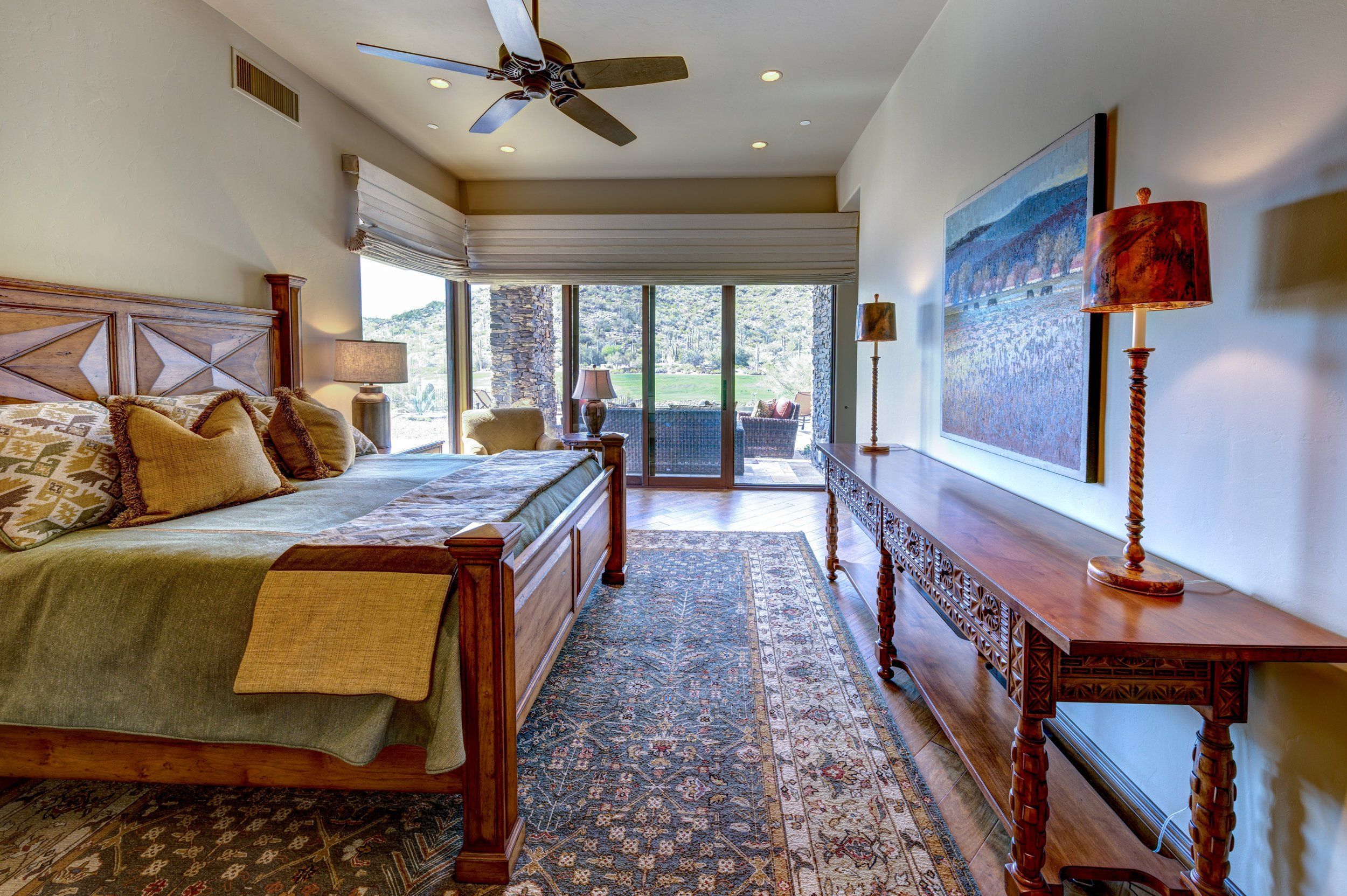 Bedroom with a carved bed, console table and sliding doors to the patio
