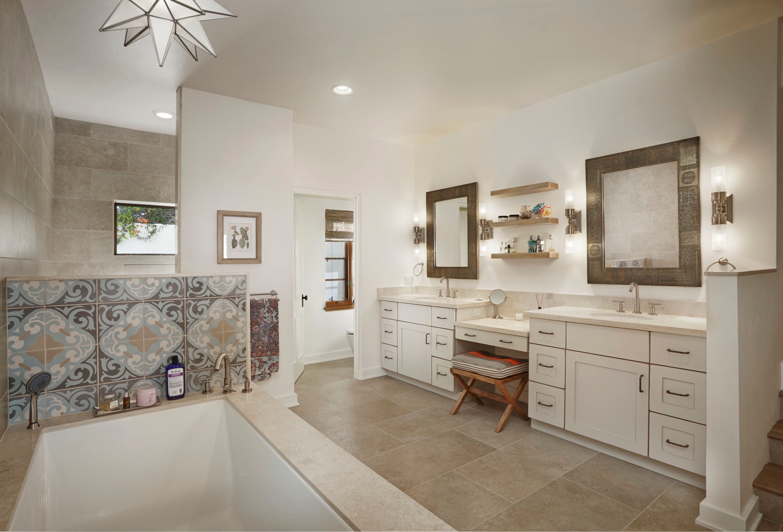 Bathroom with a star pendant, patterned tile tub surround and double vanity