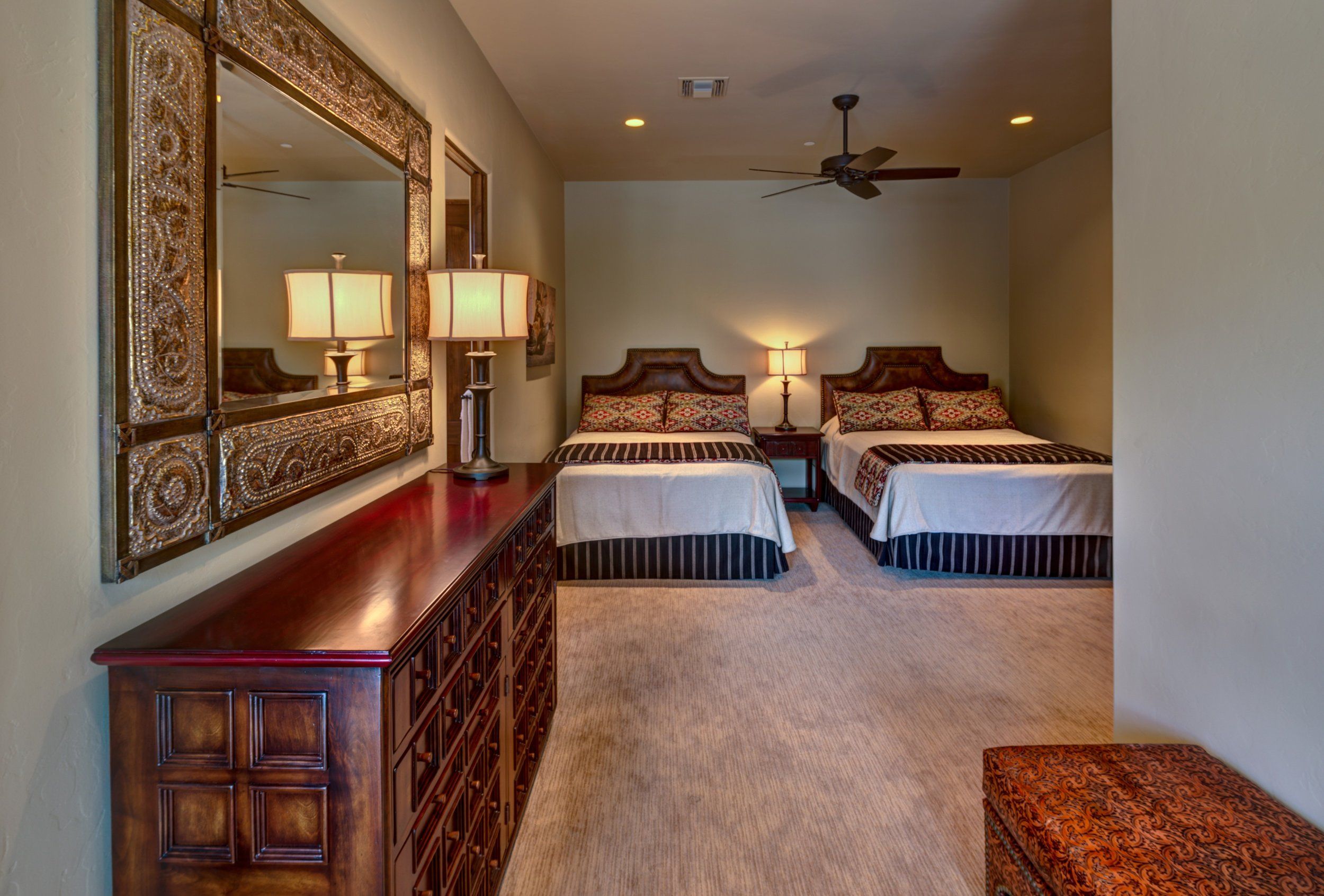 Twin-bed guest room with an ornate mirror and carved wood dresser