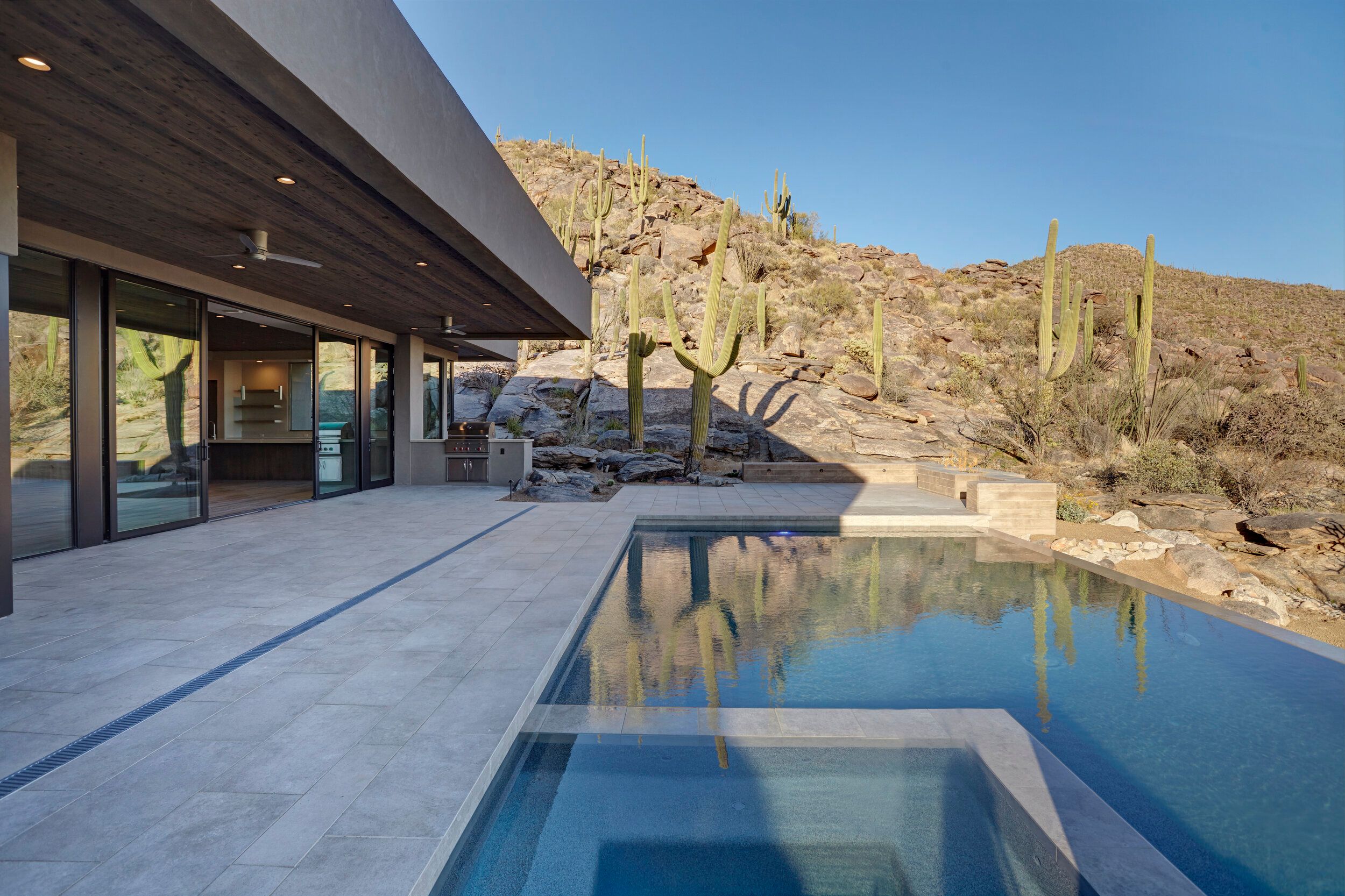 Pool and spa on the terrace beneath the boulder hillside and saguaros