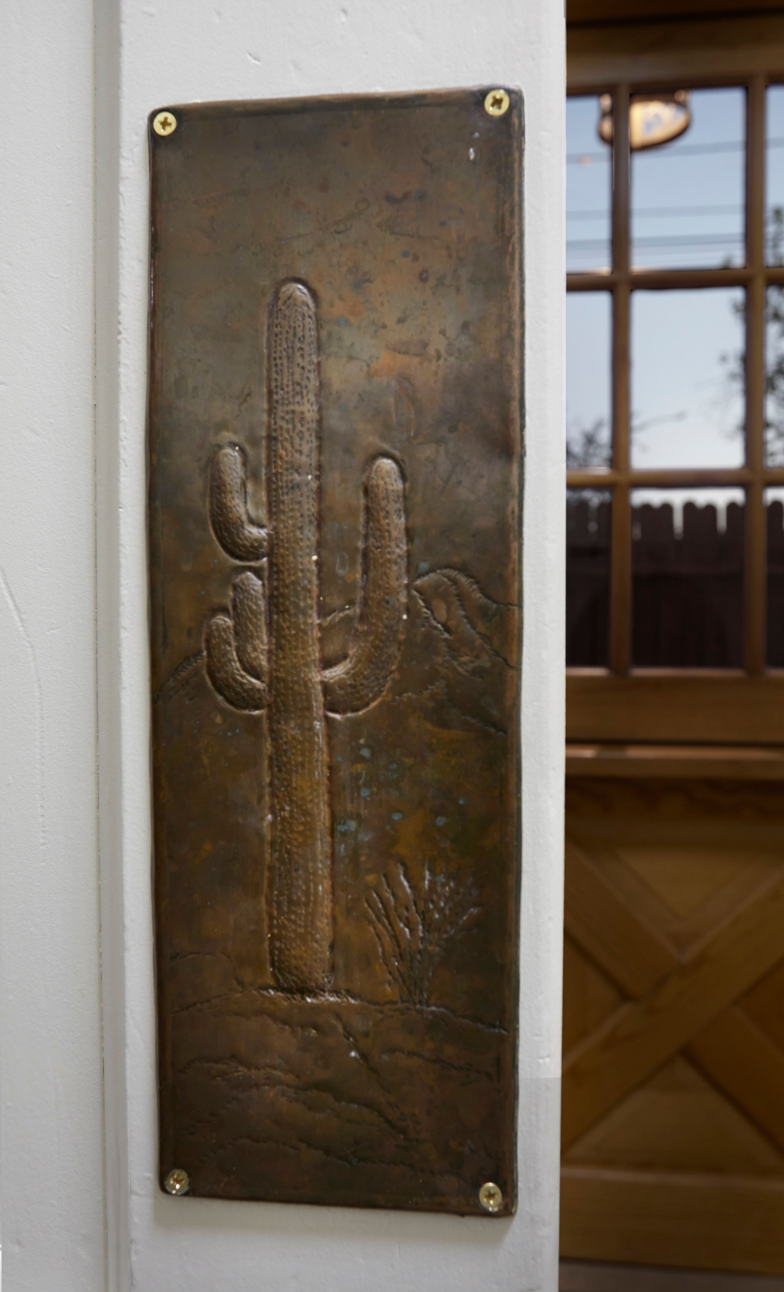 Cast bronze saguaro relief panel mounted beside the entry door