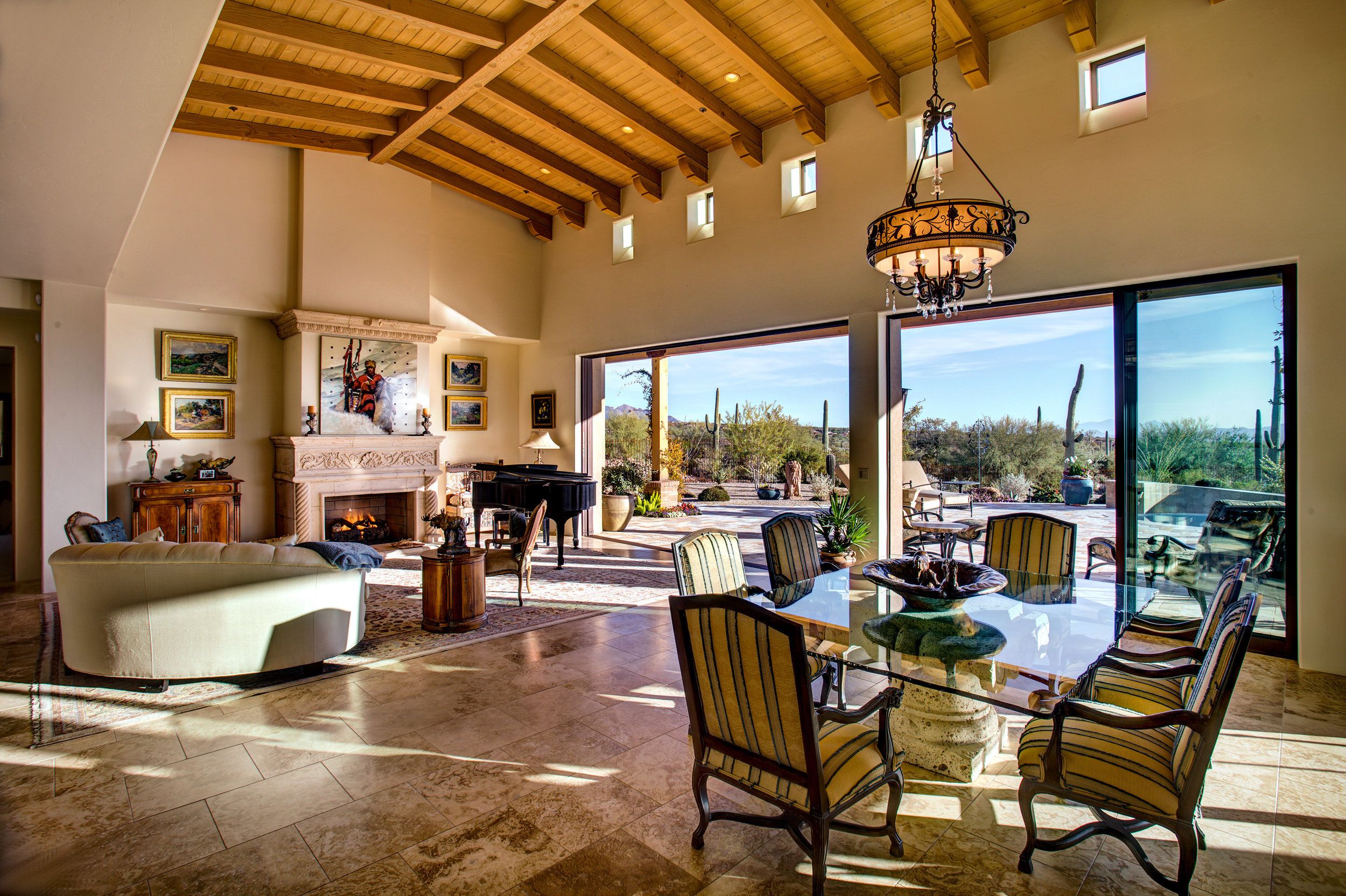 Great room with a vaulted beamed ceiling, stone fireplace and glass wall onto the covered patio