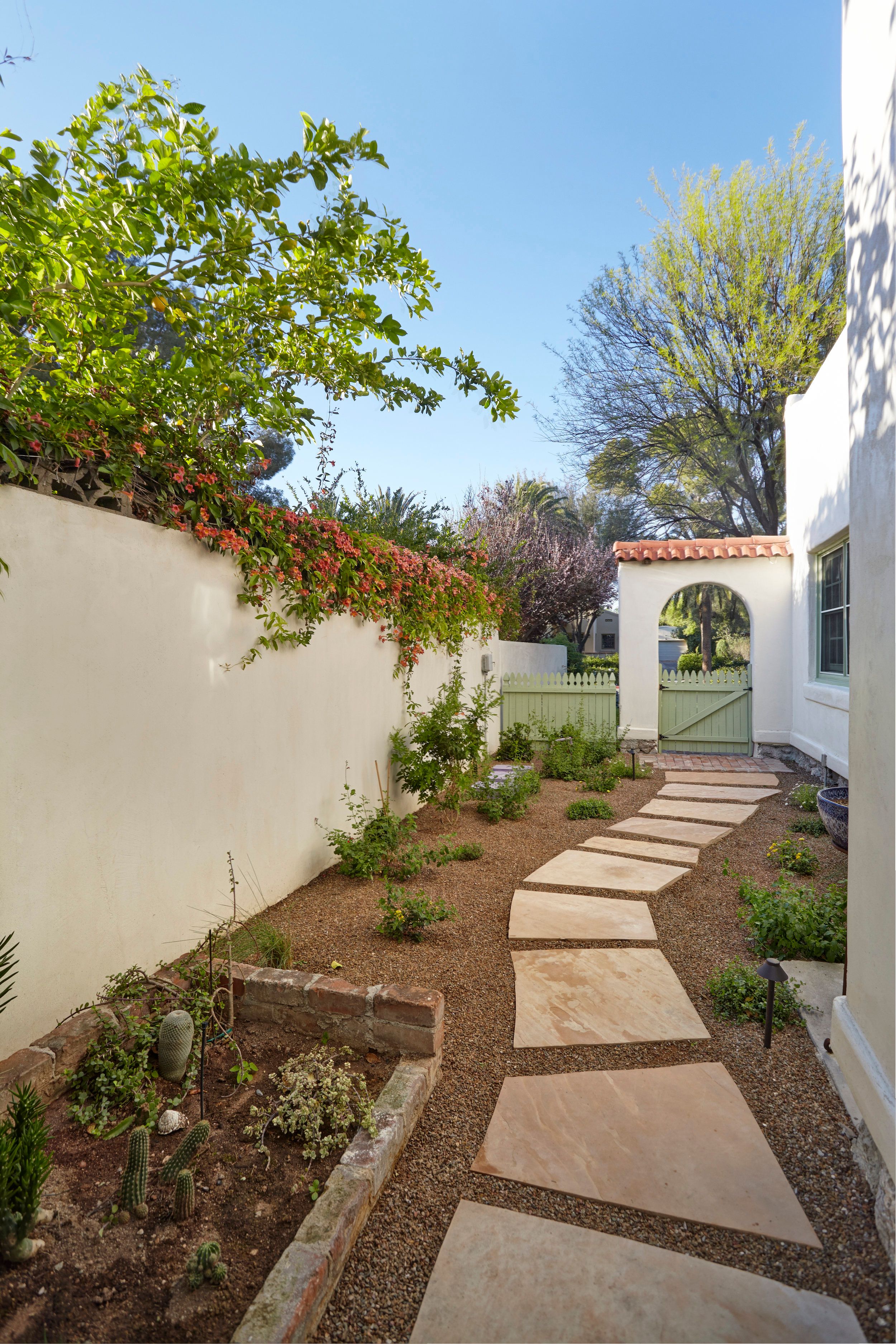 Side garden path of flagstone pavers between white stucco walls