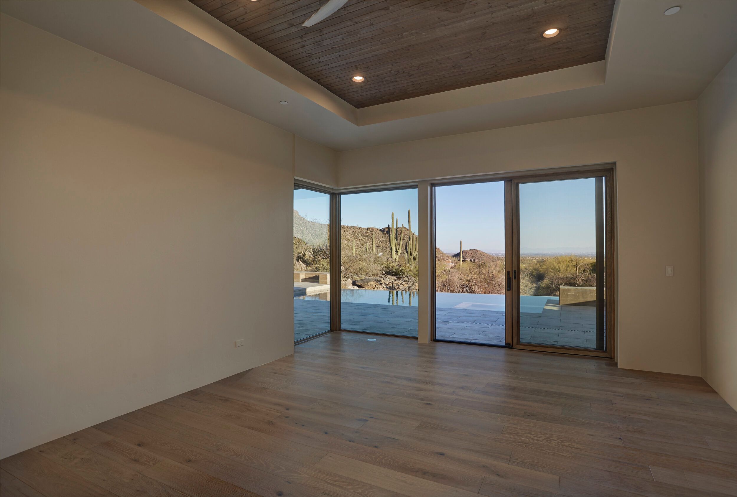 Bedroom with a wood-plank tray ceiling and sliding doors to the pool terrace