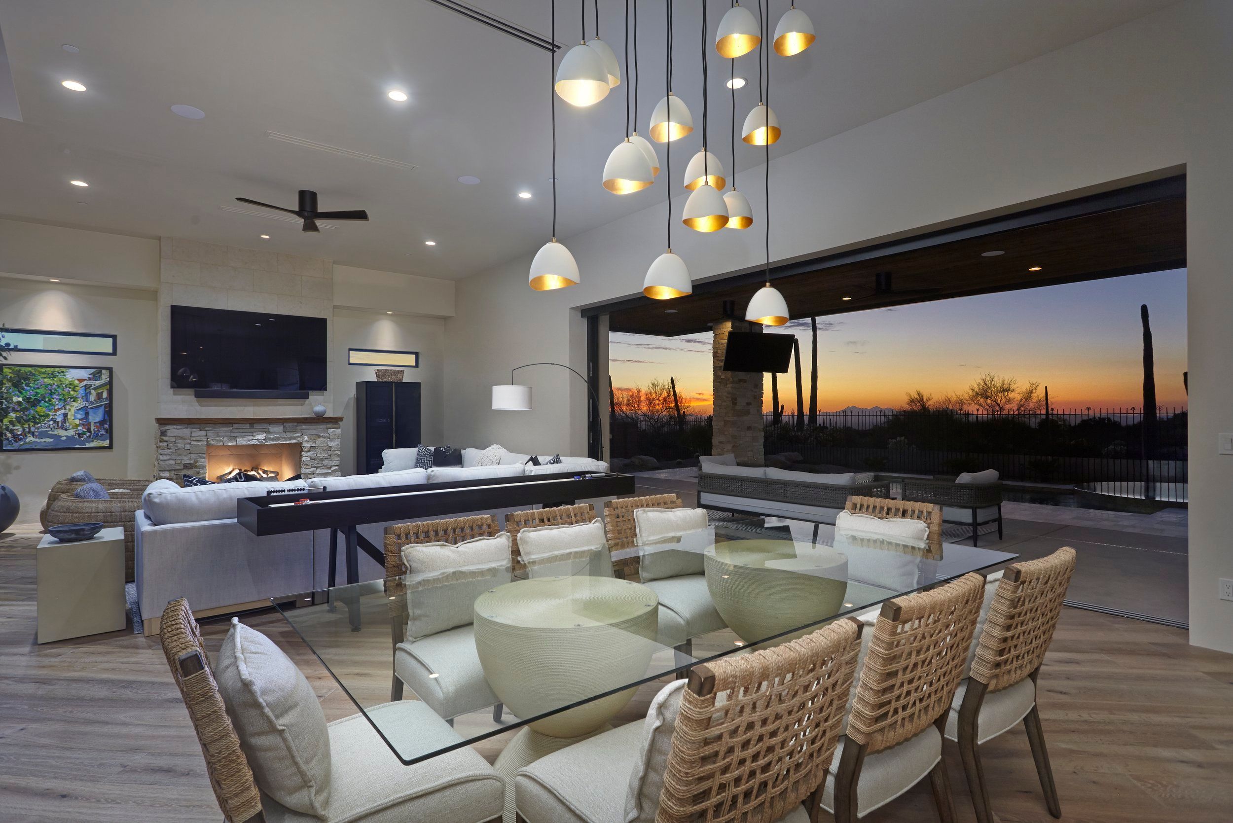 Great room and dining area at sunset with pocketing glass doors to the patio