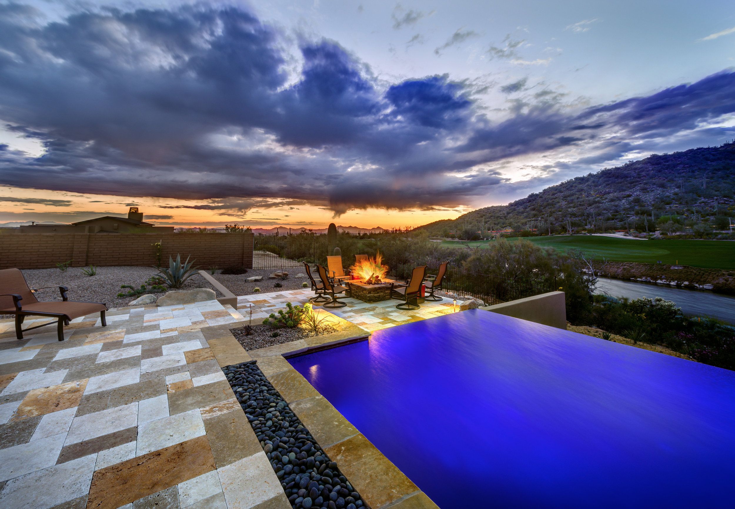 Pool and fire feature at sunset overlooking the golf course and hills