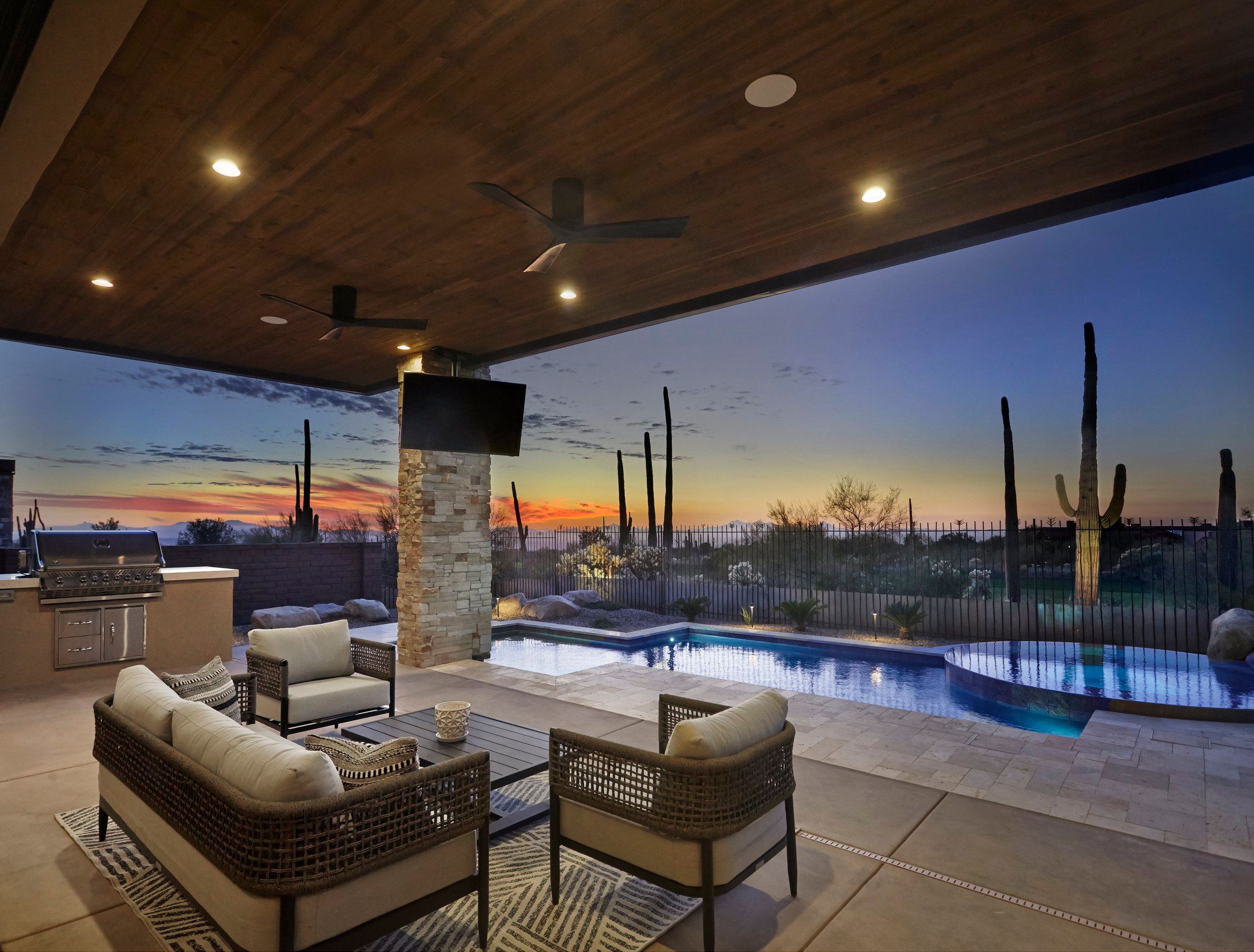 Covered patio at sunset with lounge seating, an outdoor kitchen and lit pool