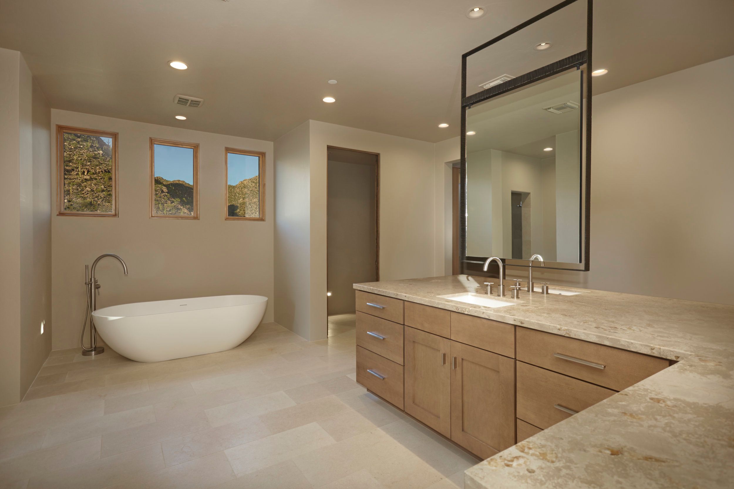 Primary bathroom with a freestanding tub, long vanity and framed mirror