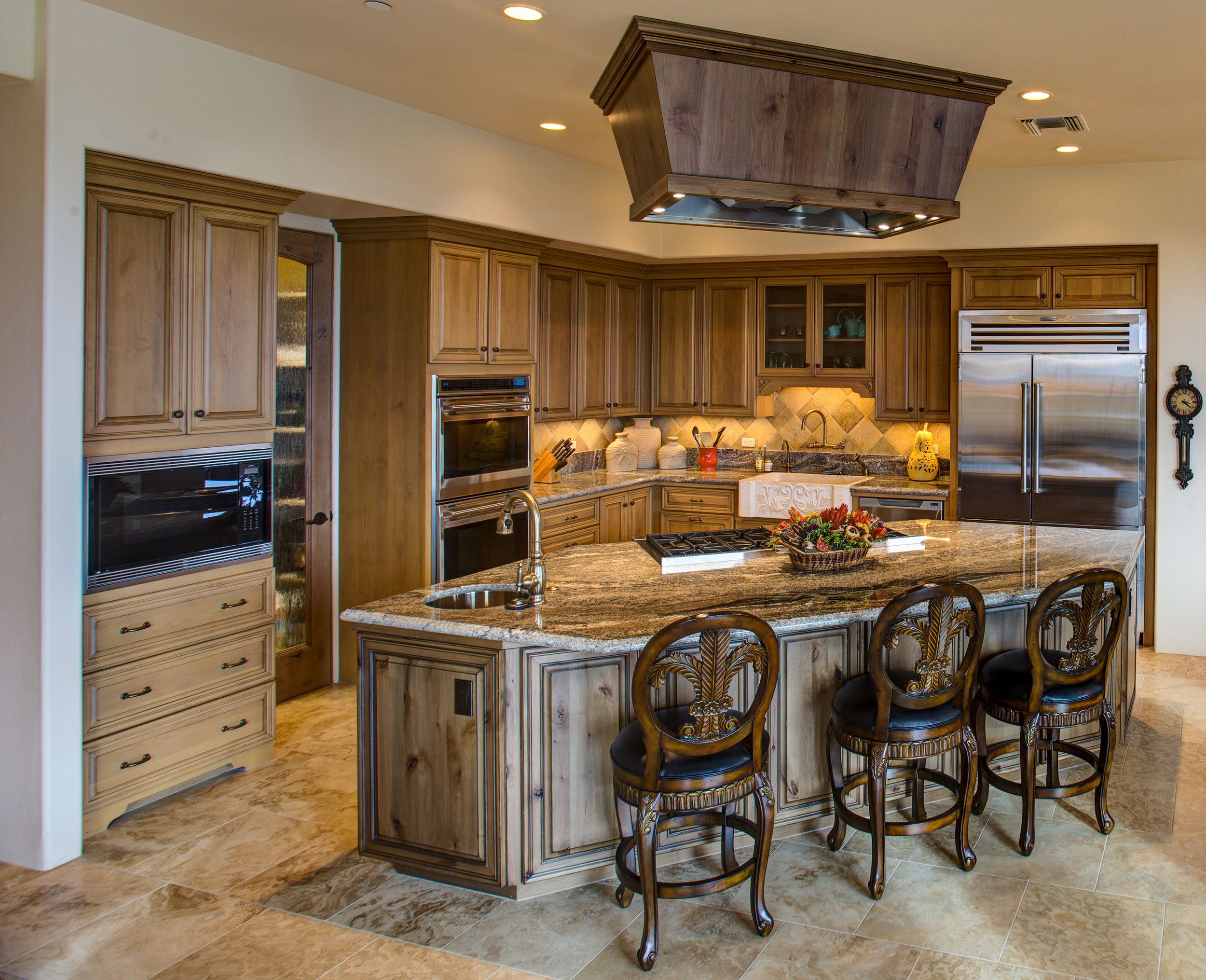 Kitchen with a granite island, glazed cabinetry and stacked double wall ovens