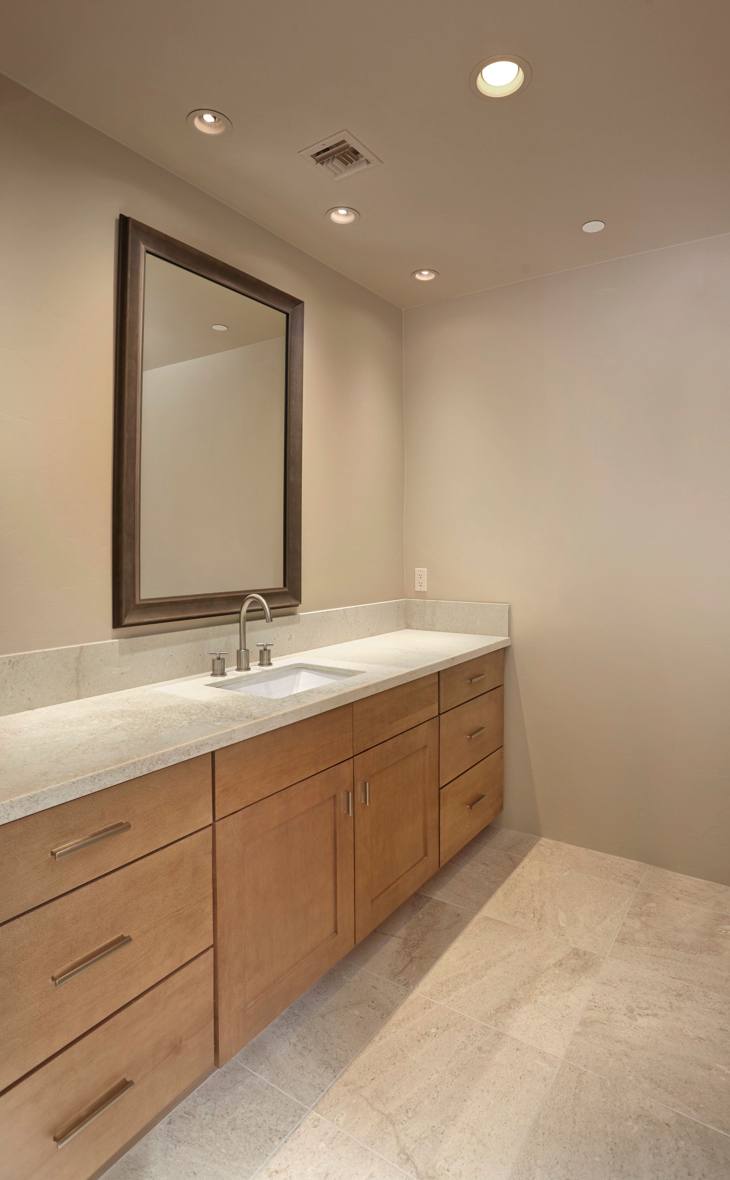 Guest bathroom vanity with a stone counter and framed mirror