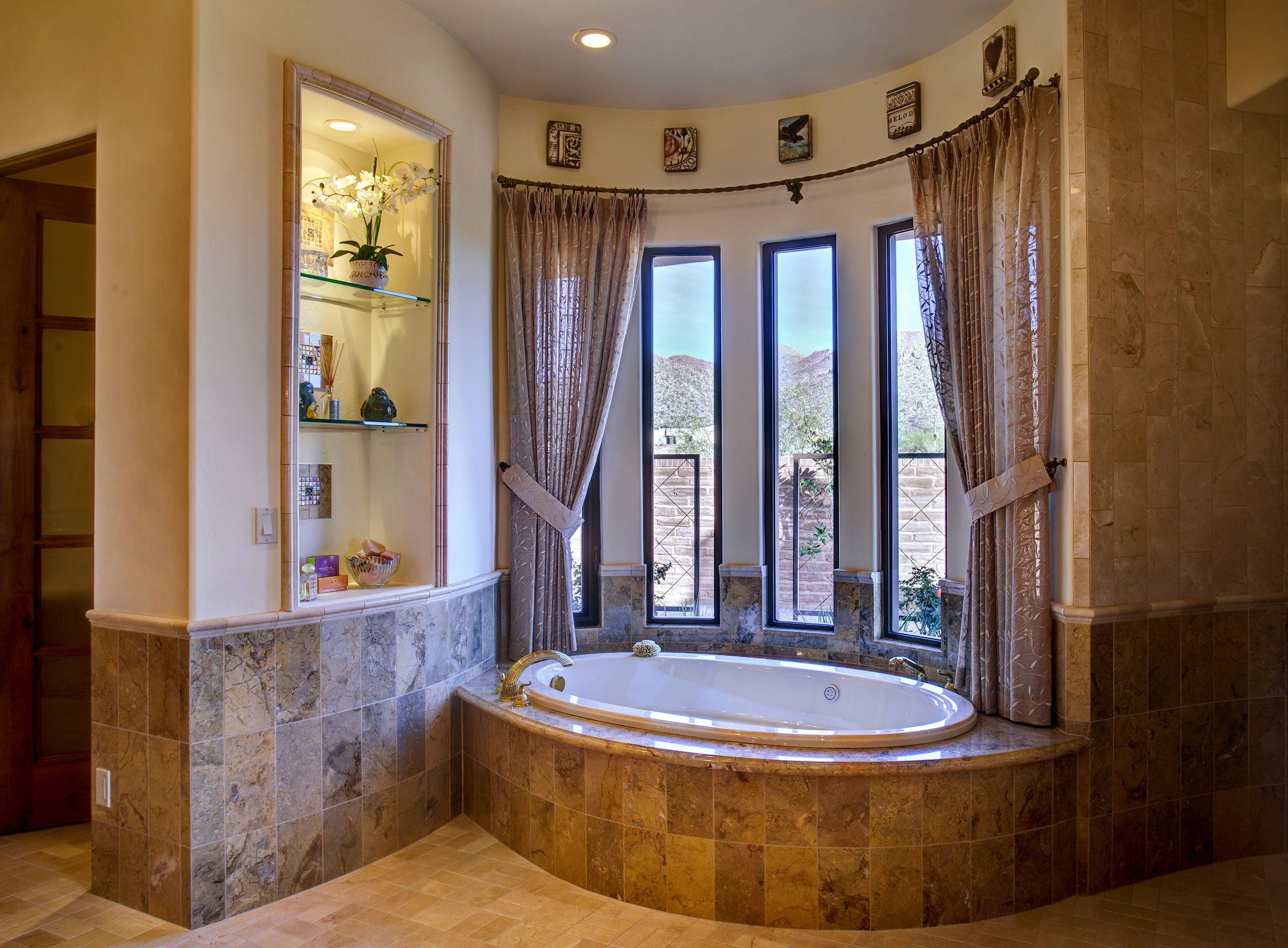 Curved bay of windows above a corner soaking tub set in travertine