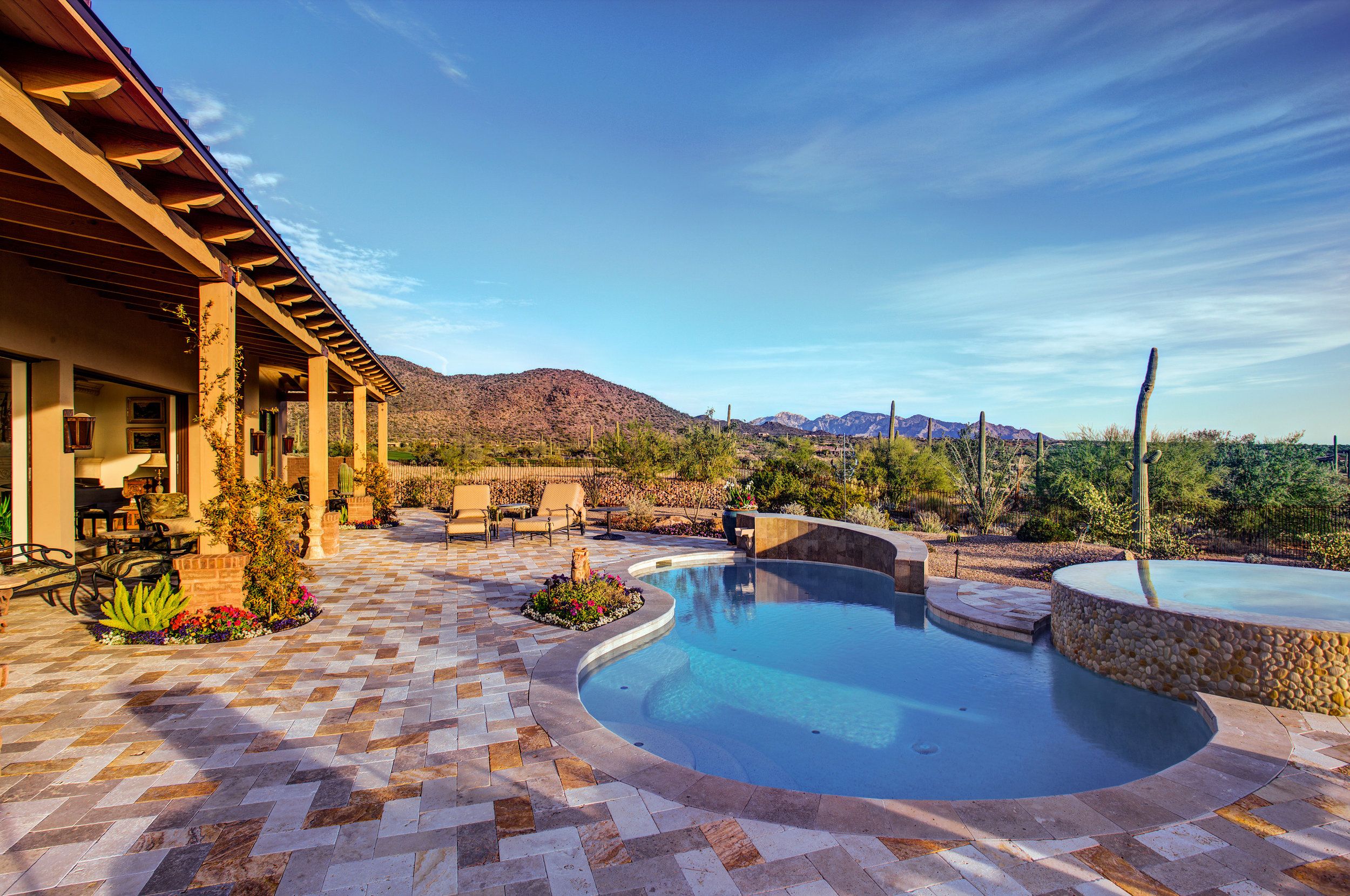 Free-form pool and spa on a travertine deck with mountain views beyond