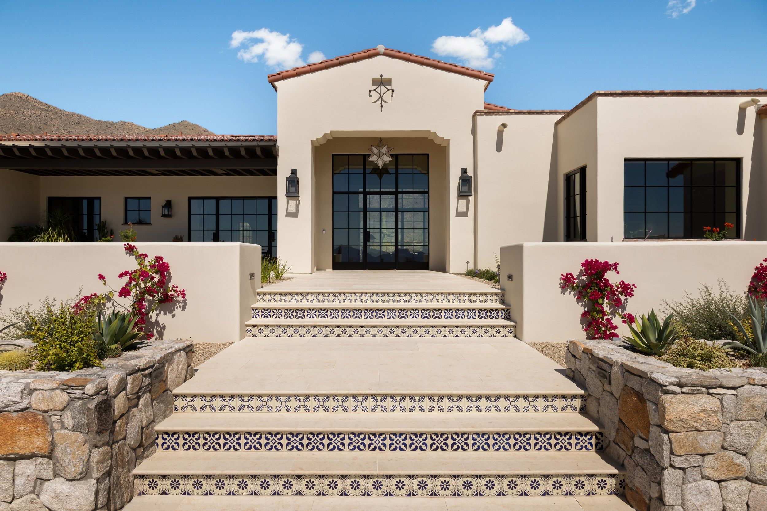 Front entry with tiled steps, stone walls and a bell alcove above the door