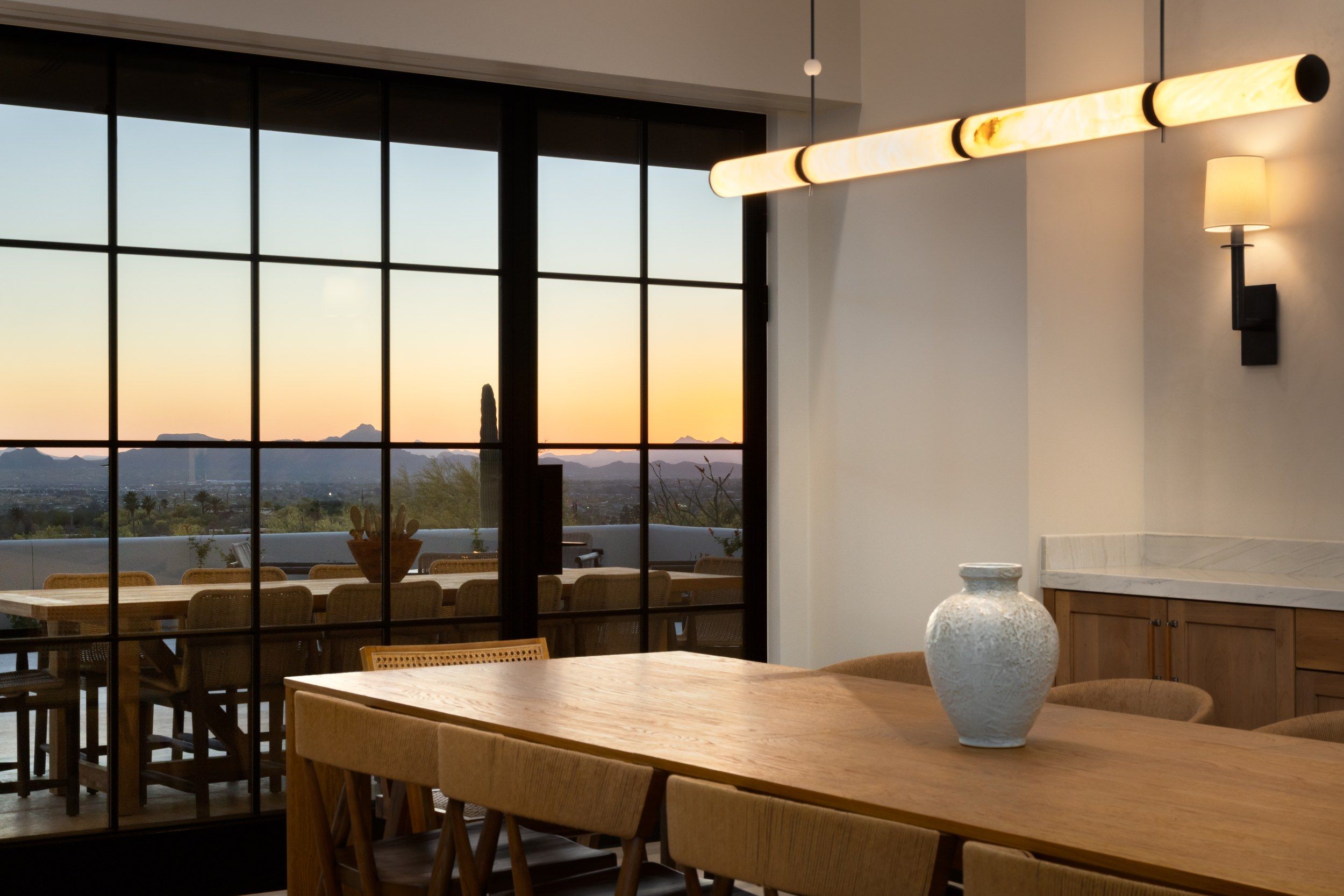 Dining room at sunset with a linear pendant and views over the desert